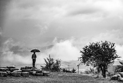 Man with umbrella against sky during rainy season