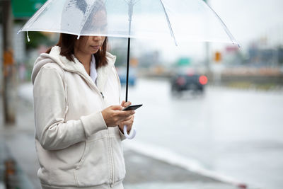 Woman using phone while standing outdoors