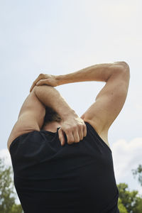 Midsection of woman with arms raised standing against sky