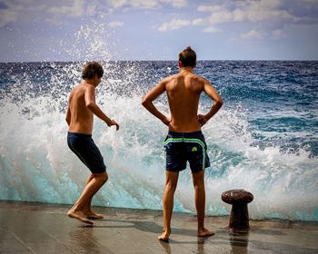 Rear view of shirtless man standing in sea against sky