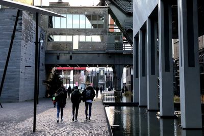 Rear view of people walking near modern buildings in city