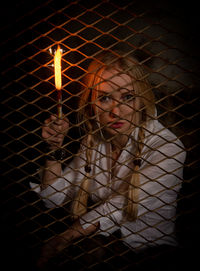 Portrait of young woman standing by fence