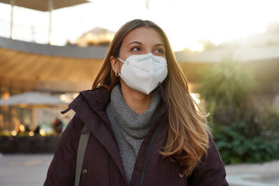 Confident woman wearing medical face mask in city street as prevention against virus