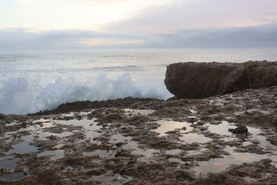 Scenic view of rocks on beach against sky