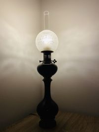 Close-up of light bulb on table against wall at home