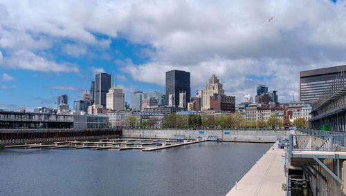 Bridge over river by buildings in city against sky