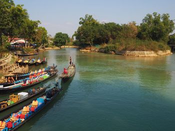 People in boat by river against trees