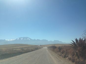 Dirt road amidst landscape against clear blue sky
