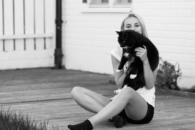 Portrait of teenage girl playing with cat outdoors