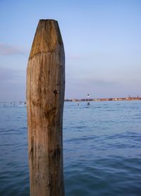 Wooden posts in sea against sky