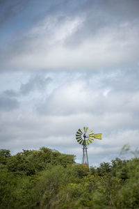 Low angle view of wind turbines on landscape against sky