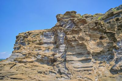 Low angle view of rock formations against clear blue sky