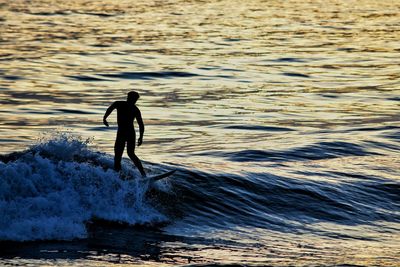 Silhouette man surfing in sea during sunset