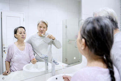 Senior couple brushing teeth while looking in mirror