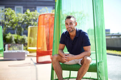 An outdoor portrait of a man in a colorful modern chair.