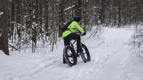 Rear view of man cycling on snow covered land