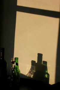 Close-up of bottles on table against wall at home