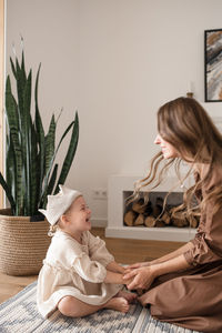 Mother holds the hands of her baby daughter while playing together.