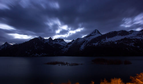 Scenic view of lake and mountains against dramatic sky