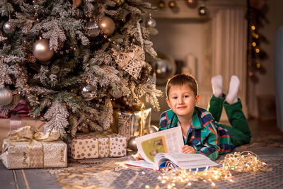 Full length of boy in illuminated christmas tree