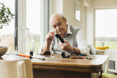 Senior man repairing toy train at home