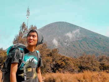 Man looking away while standing against mountains