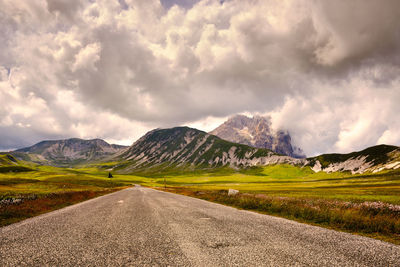 Road leading towards mountains against sky