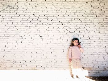 Thoughtful girl looking away while leaning on wall