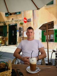 Portrait of man sitting at sidewalk cafe