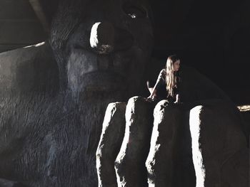 Young woman sitting on sculpture