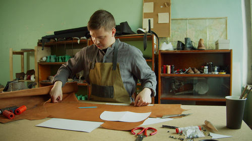 Full length of man holding paper on table