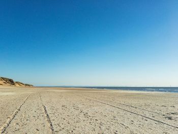 Scenic view of beach against clear blue sky