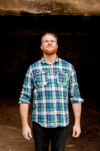 Portrait of young man standing against wall