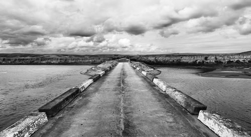 Road leading towards cloudy sky