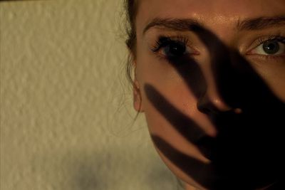 Close-up portrait of serious young woman against wall