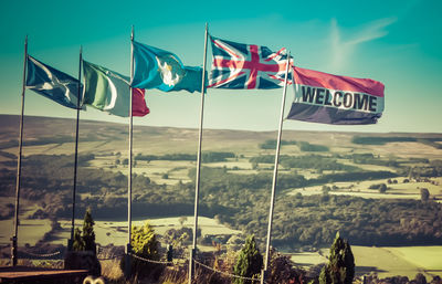 Close-up of flags on landscape against sky