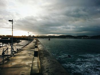 Pier on sea against cloudy sky