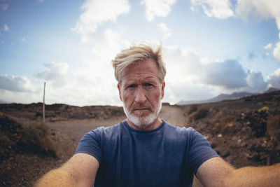 Portrait of young man standing against sky