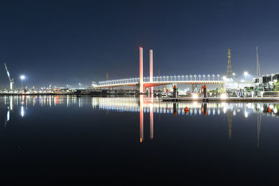 Illuminated bridge over river against sky at night