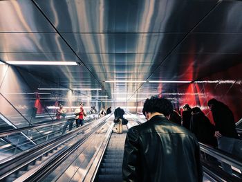 Rear view of man standing on escalator in city