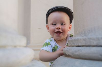 Portrait of cute cheerful baby boy by column