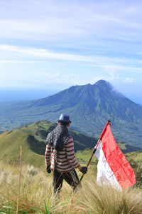 Men and the red and white flag on the top of mount merbabu, indonesia