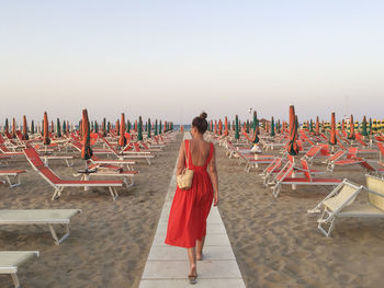 Rear view of woman standing on beach against clear sky