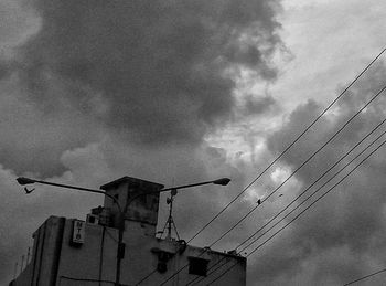 Low angle view of crane against cloudy sky