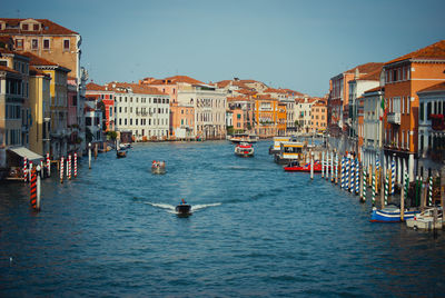 Boats in canal amidst buildings against clear sky