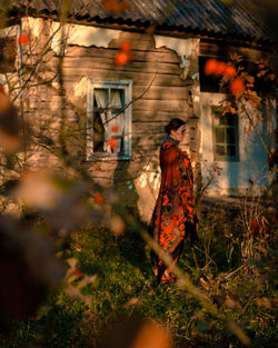 Portrait of ukrainian woman in a colorful knitted scarf near wooden house on a summer evening 