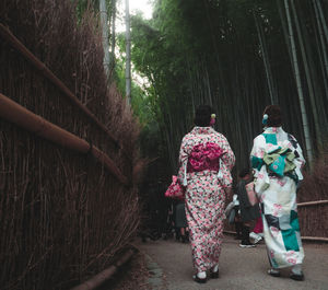 Rear view of women walking on footpath in forest