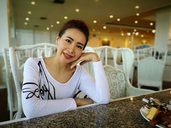 Portrait of woman smiling while sitting at table in restaurant