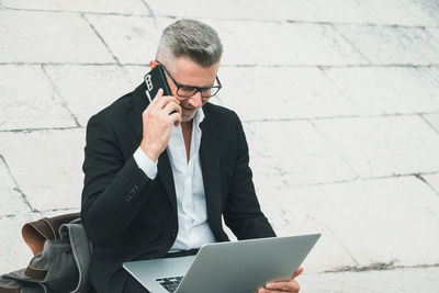 Young man using mobile phone while sitting outdoors