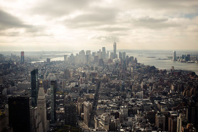 Aerial view of buildings in city against cloudy sky